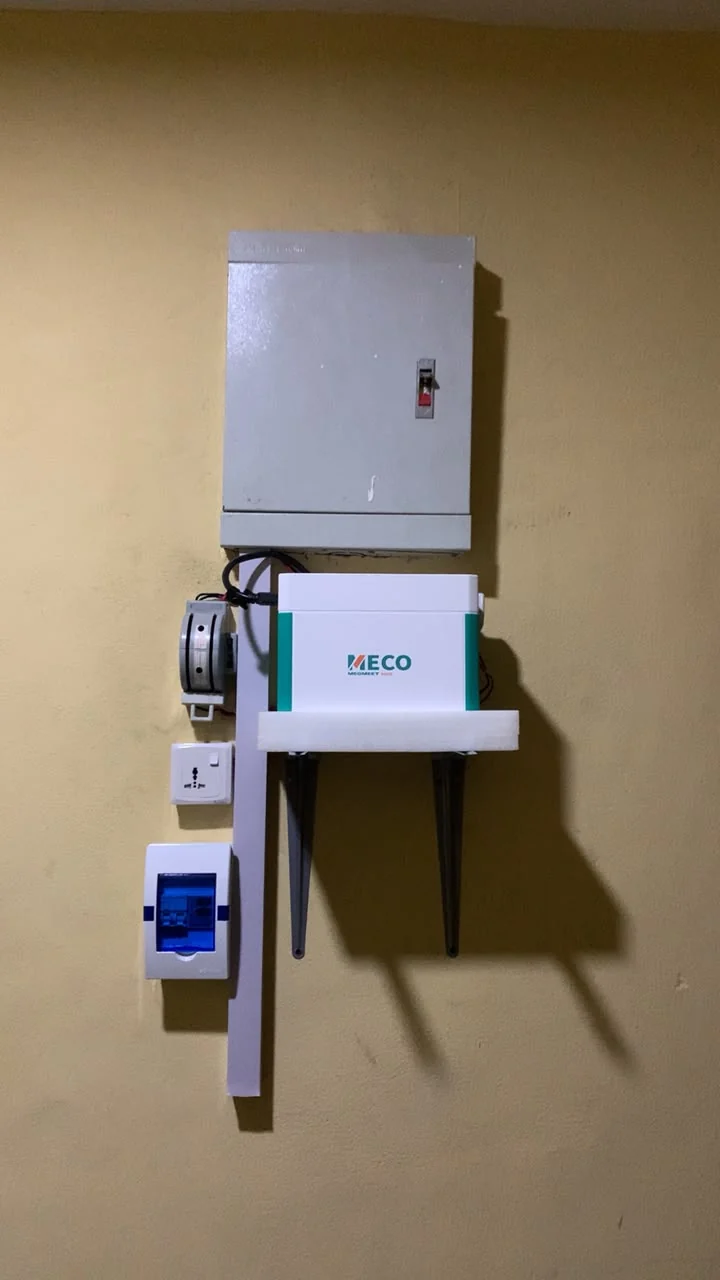 White-and-green MECO 1000 unit wall-mounted below a metal electrical enclosure, with protective distribution equipment